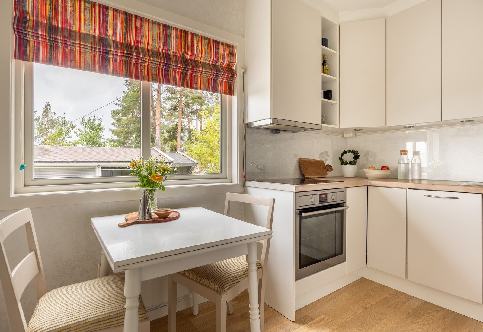 Pent kjøkken fra 2013 med glatte lyse fronter og benkeplater av heltre. Galleribilde