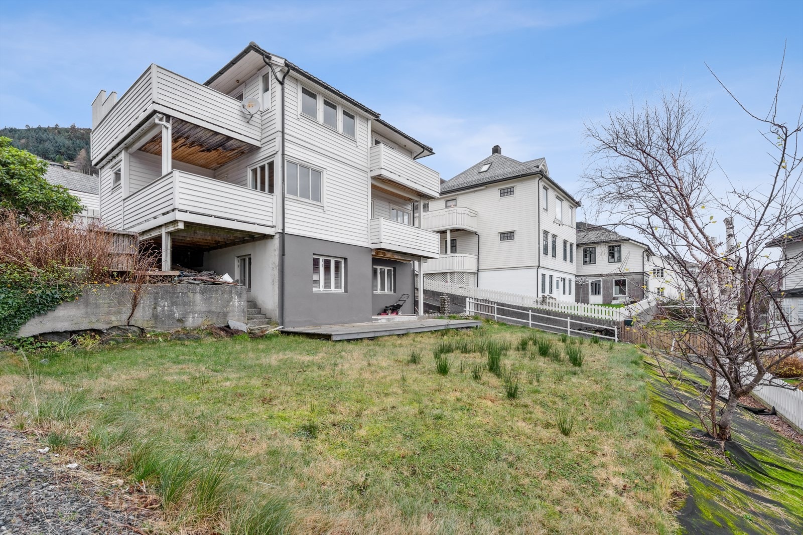 Opparbeidet hage på nedsiden av huset med plen og beplantning Galleribilde