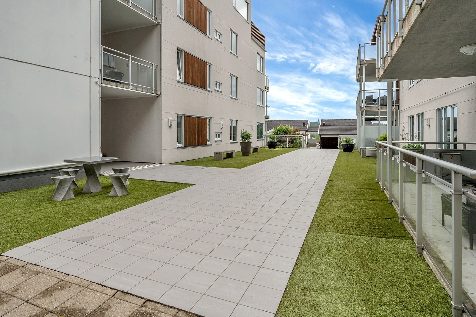 Pent opparbeidede fellesområder med beplantning og sitteplasser. Galleribilde