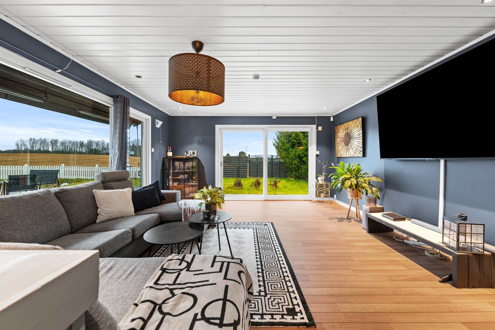 Store vinduer gir godt lysinnslipp og utsikt til hagen. Veggene er malt i en dyp blåfarge Galleribilde