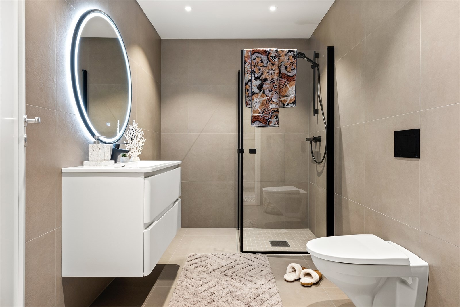 Bilde fra Granveien 38A. Badet er helfliset med moderne fargevalg, vegghengt toalett og dusjhjørne med innfellbare glassdører. Galleribilde