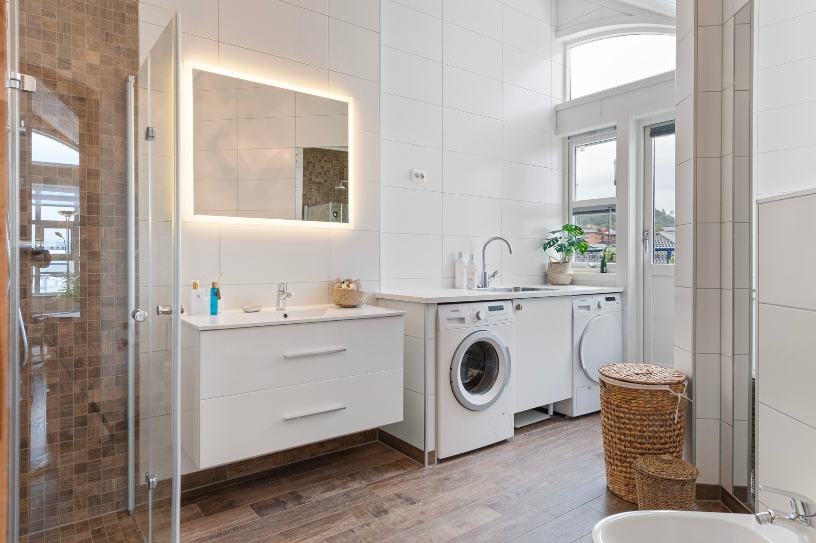 Stort bad med integrert vaskemaskin og tørketrommel som følger boligen Galleribilde