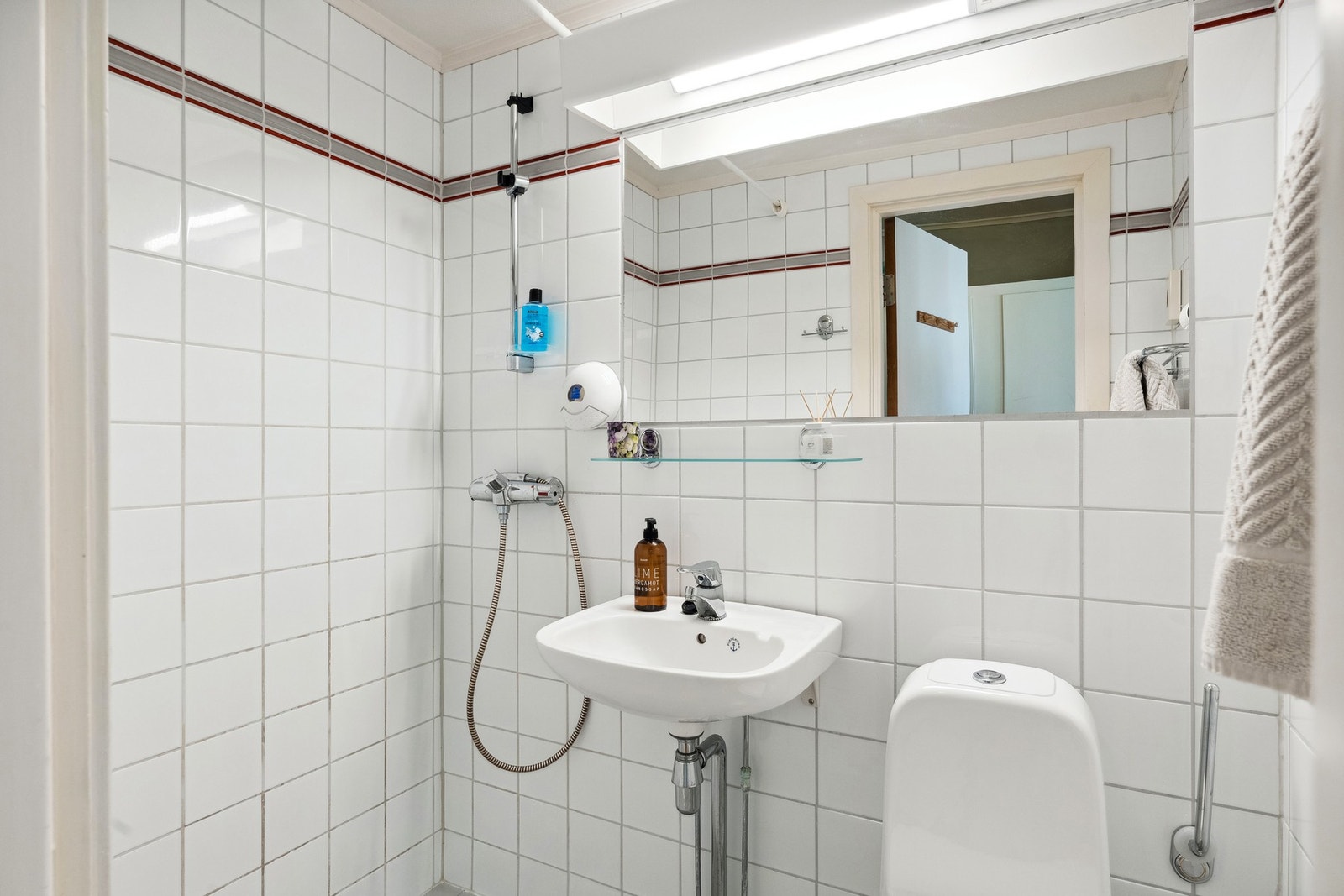 Bad 2 har også flisbelagt overflater med varme i gulvet. Det er montert vegghengt porselenservant, gulvstående toalett, vegghengt speil og åpen dusj i hjørne. Dette badet har opplegg for vaskemaskin. Galleribilde