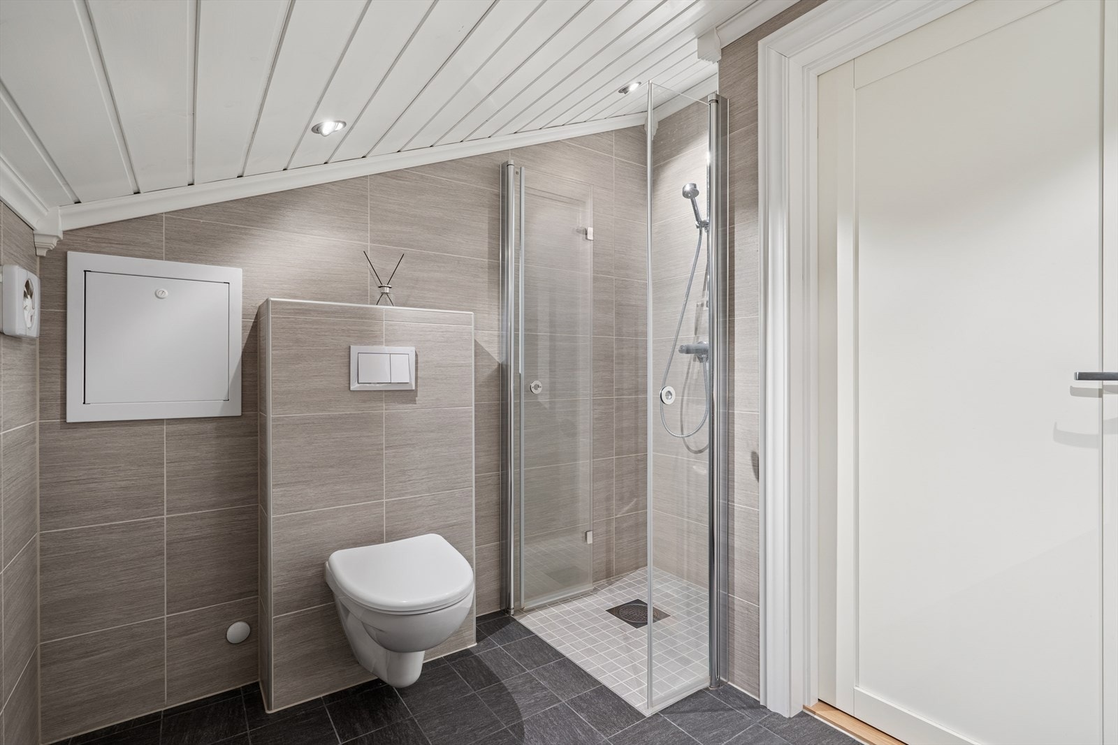 Badet i andre etasje har samme høye standard, med flislagte overflater, veggmontert toalett og dusjnisje med glassdør. Galleribilde