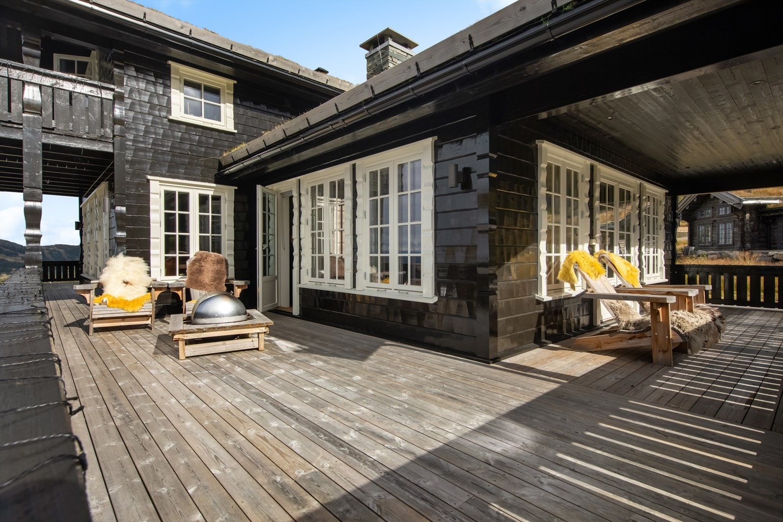 Romslig terrasse i impregnert tre, delvis overbygget for ly mot vær og vind. Plassert på forsiden av hytta med panoramautsikt mot Gaustatoppen og Hardangervidda. Perfekt for lange sommerdager og sosiale sammenkomster Galleribilde