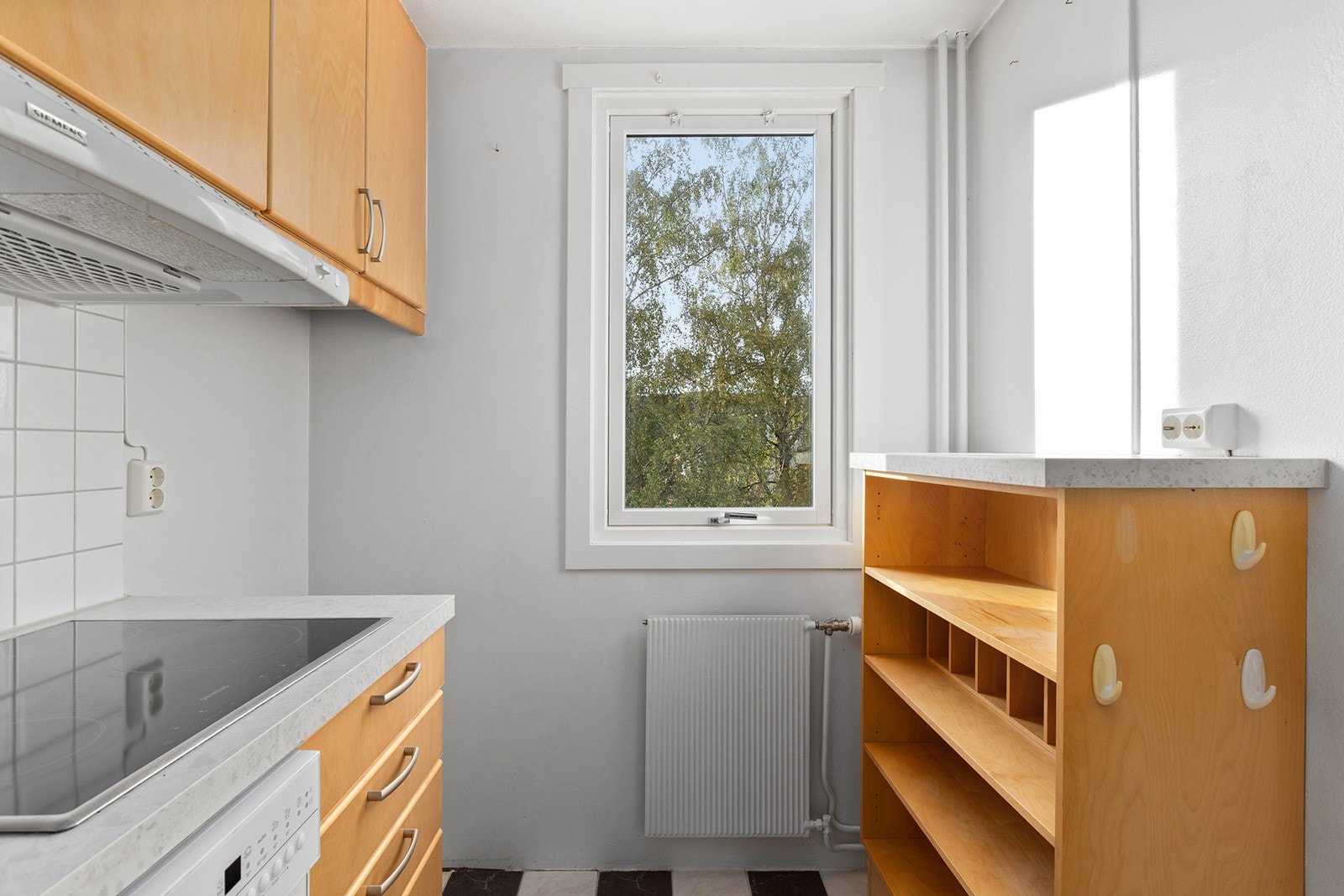 Kjøkkenet inneholder slette bjørkefronter og laminert benkeplate med fliser over. Integrert stekeovn og koketopp. Galleribilde