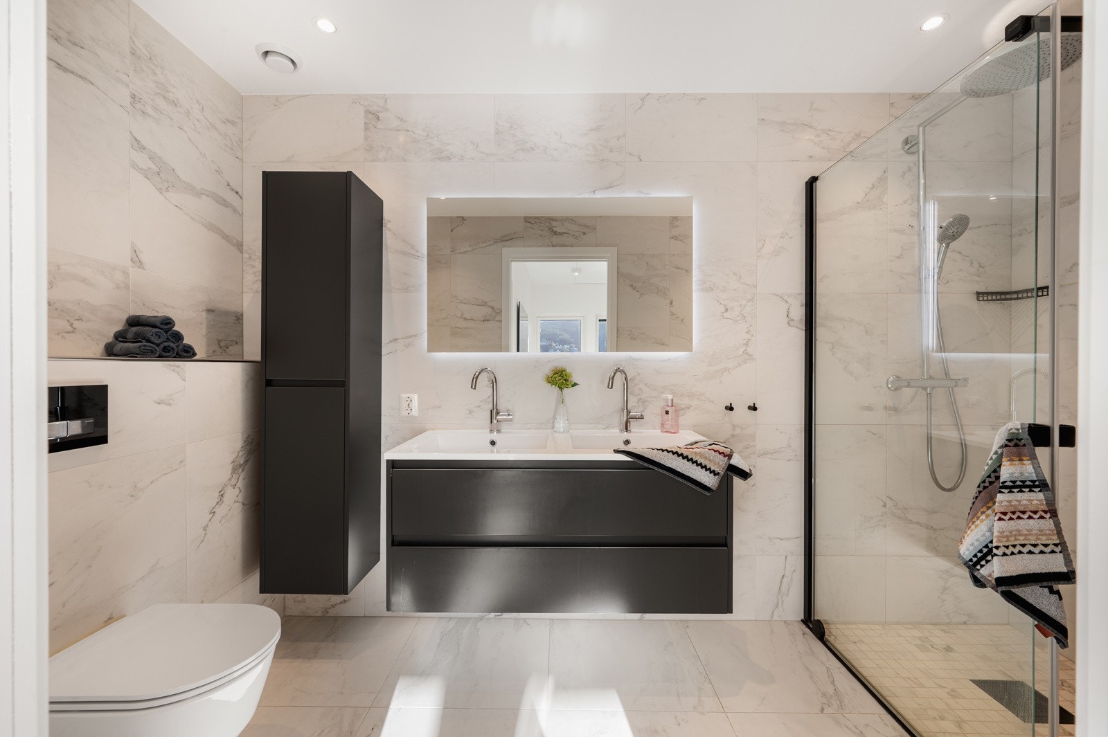 Badet på 5,8 kvadrameter har tilkomst fra hovedsoverommet og har marmor fliser på gulv og vegger. Malt platekledning i tak med spotlights. Galleribilde