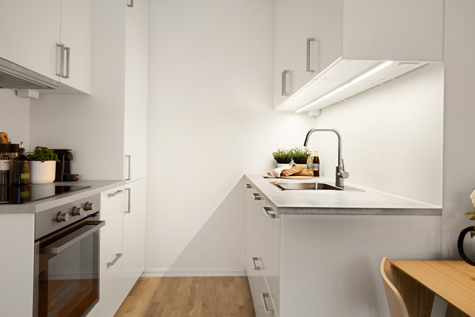 Stilrent kjøkken med integrerte hvitevarer og laminat benkeplate med nedfelt kum i rustfritt stål. Galleribilde