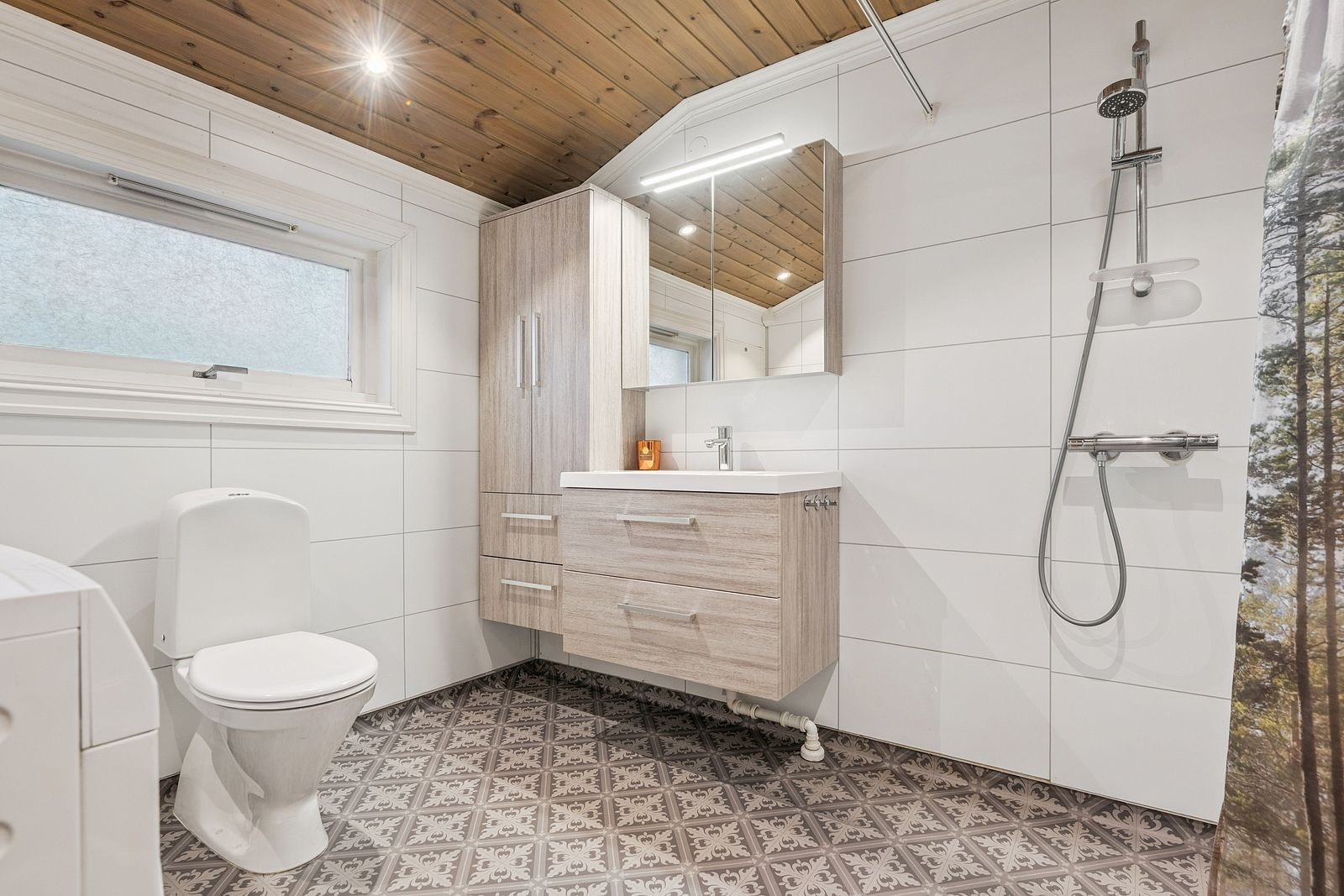 Bad med servantinnredning, speilskap med lys, dusj, toalett og opplegg for vaskemaskin. Galleribilde