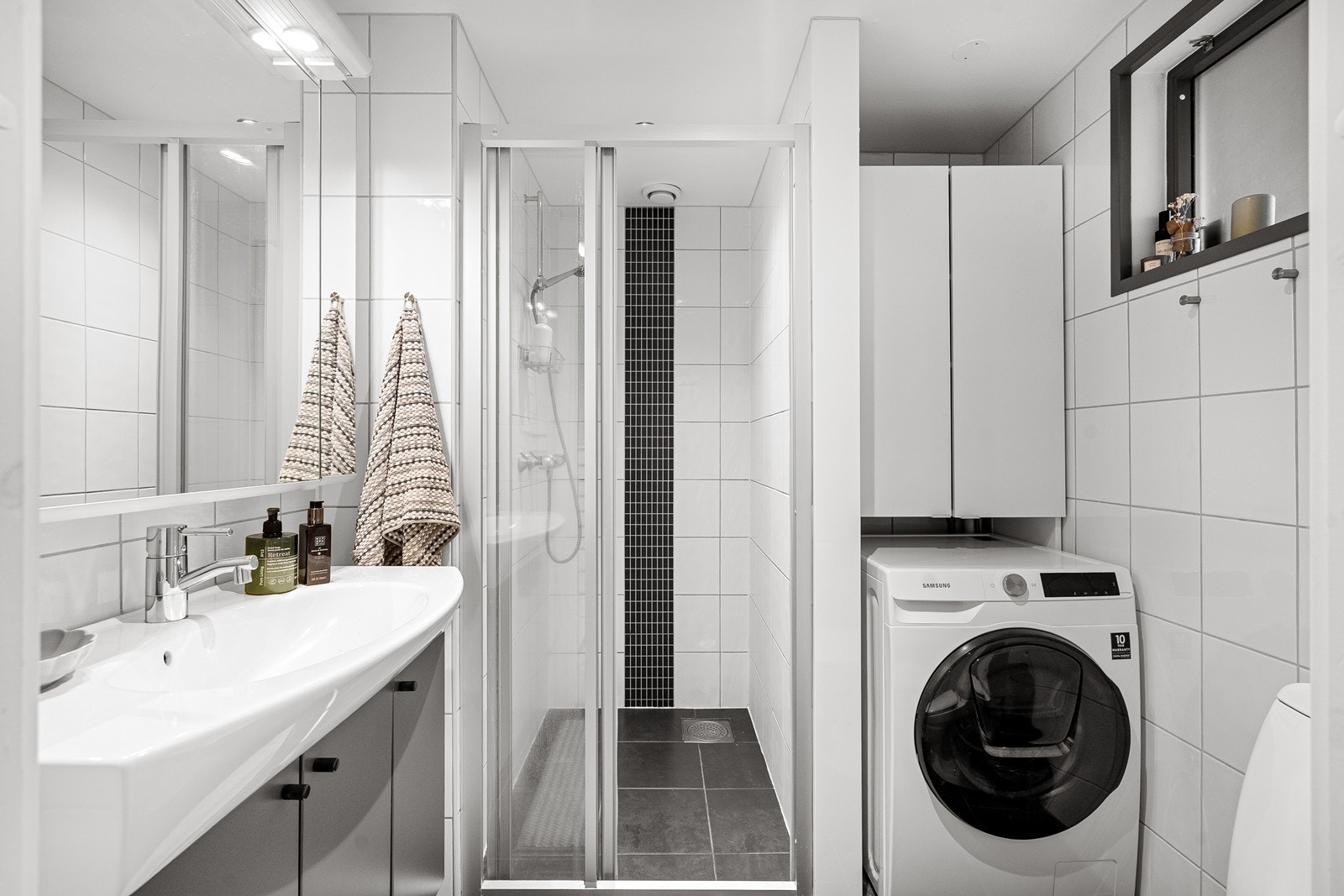 Flott flisebelagt bad er innredet med vask i seksjon, toalett og dusj. Opplegg for vaskemaskin. Galleribilde