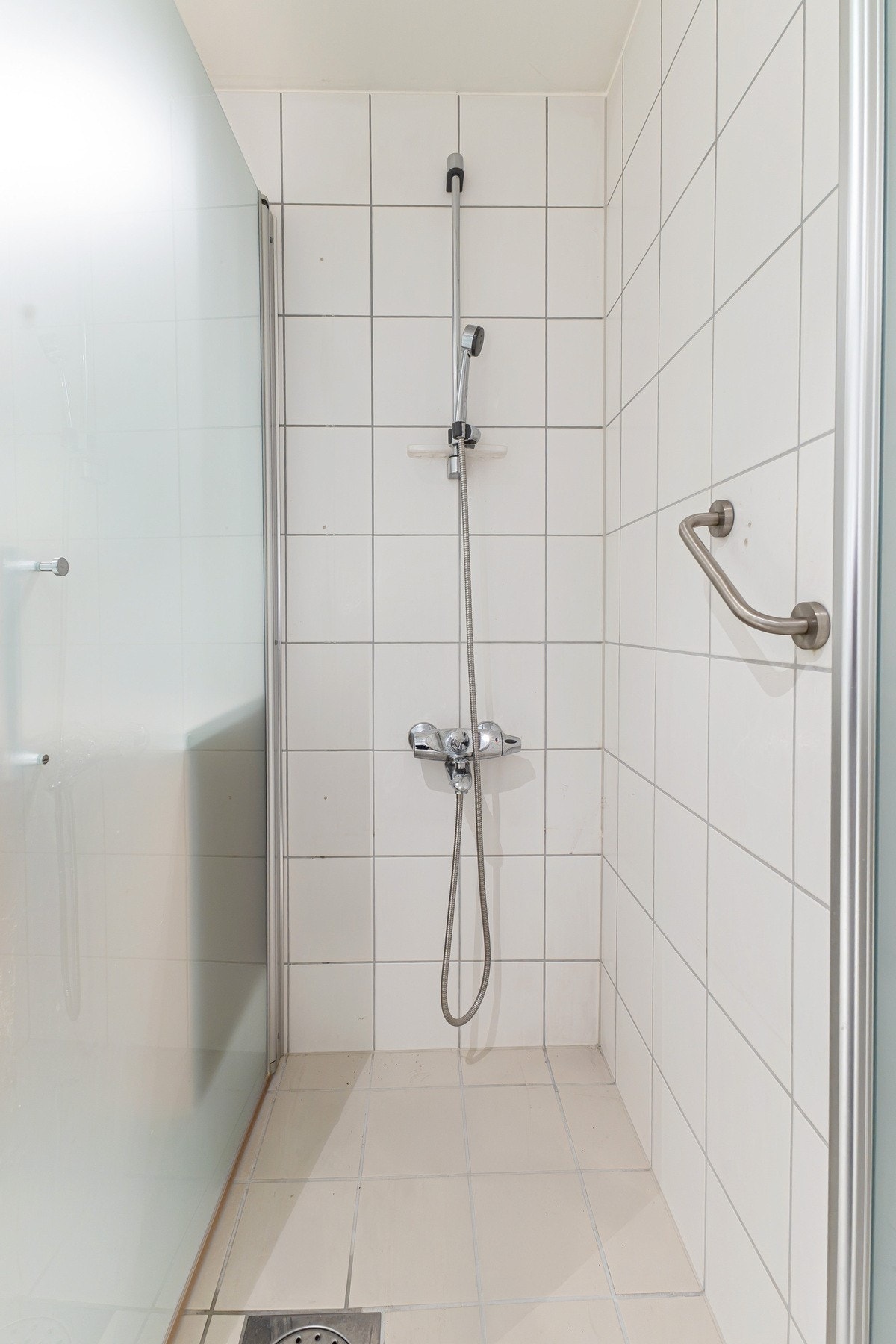 Videre inneholder badet vegghengt toalett og dusjhjørne med inn-/utadslående dører i herdet glass. Galleribilde