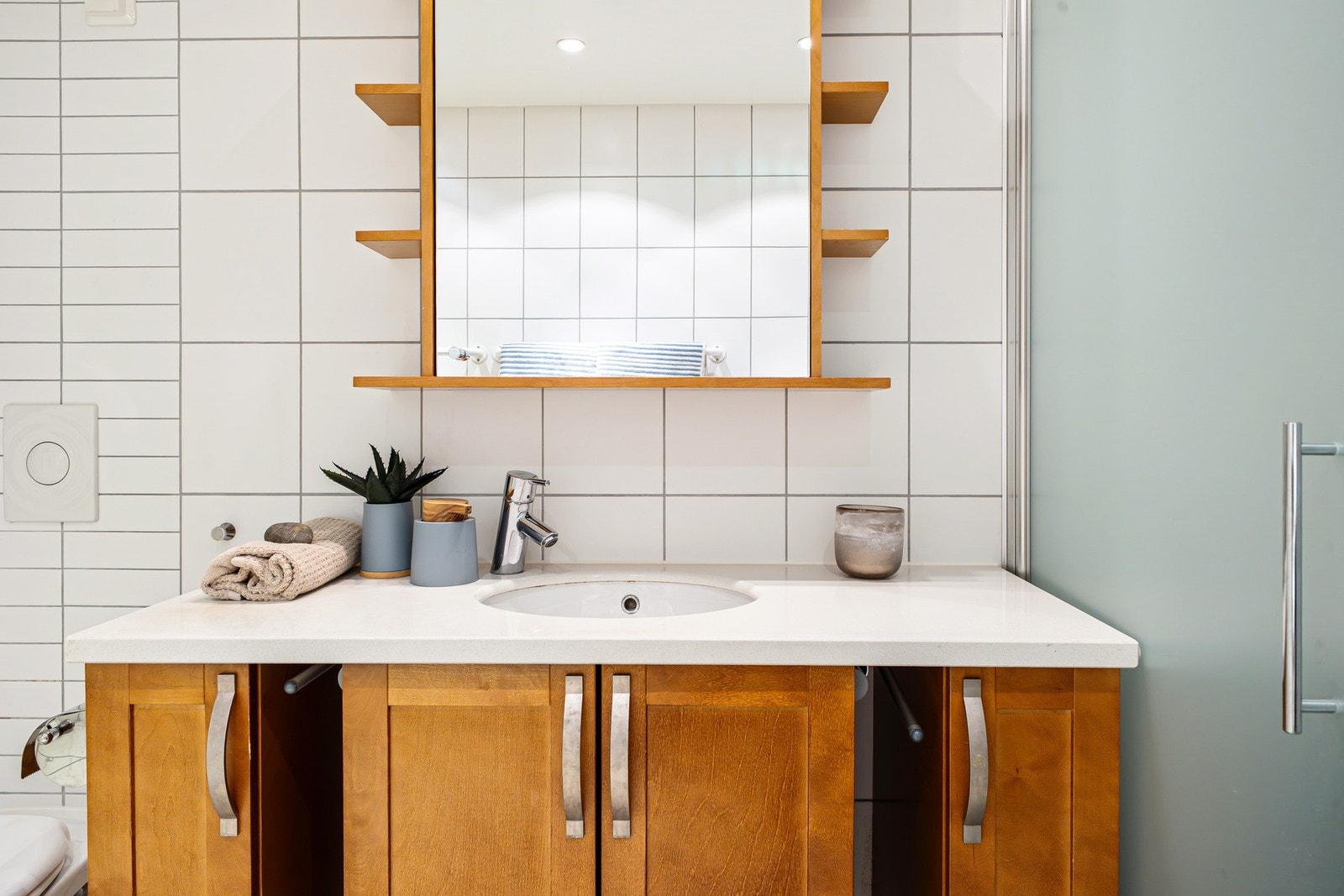 Badet har servantinnredning med skap og ovenpåliggende servant, samt speil med integrert belysning på vegg over servant. Galleribilde