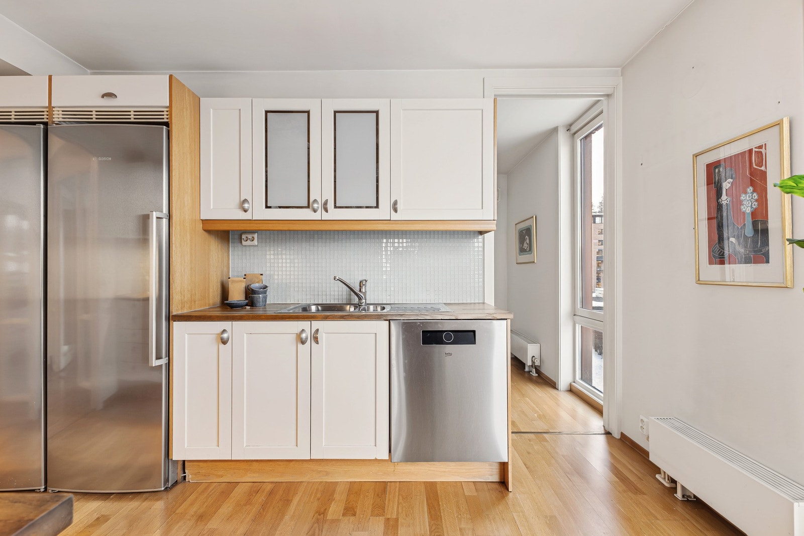 Tidløs kjøkkeninnredning med laminerte skrog, profilerte fronter med benkeplate av heltre med nedfelt oppvaskkum. Galleribilde