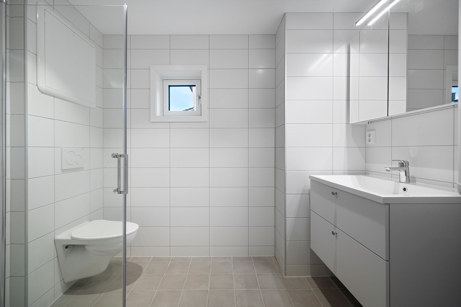 Leiligheten har et pent og moderne baderom med flislagte gulv og vegger, samt varmekabler i gulvet som gir en behagelig temperatur året rundt. Galleribilde