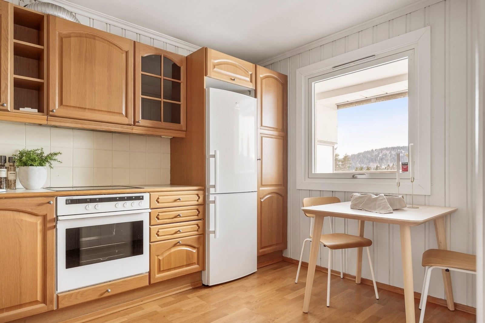 Tidløs kjøkkeninnredning med laminerte skrog, profilerte fronter med benkeplate av laminat med nedfelt oppvaskkum. Galleribilde