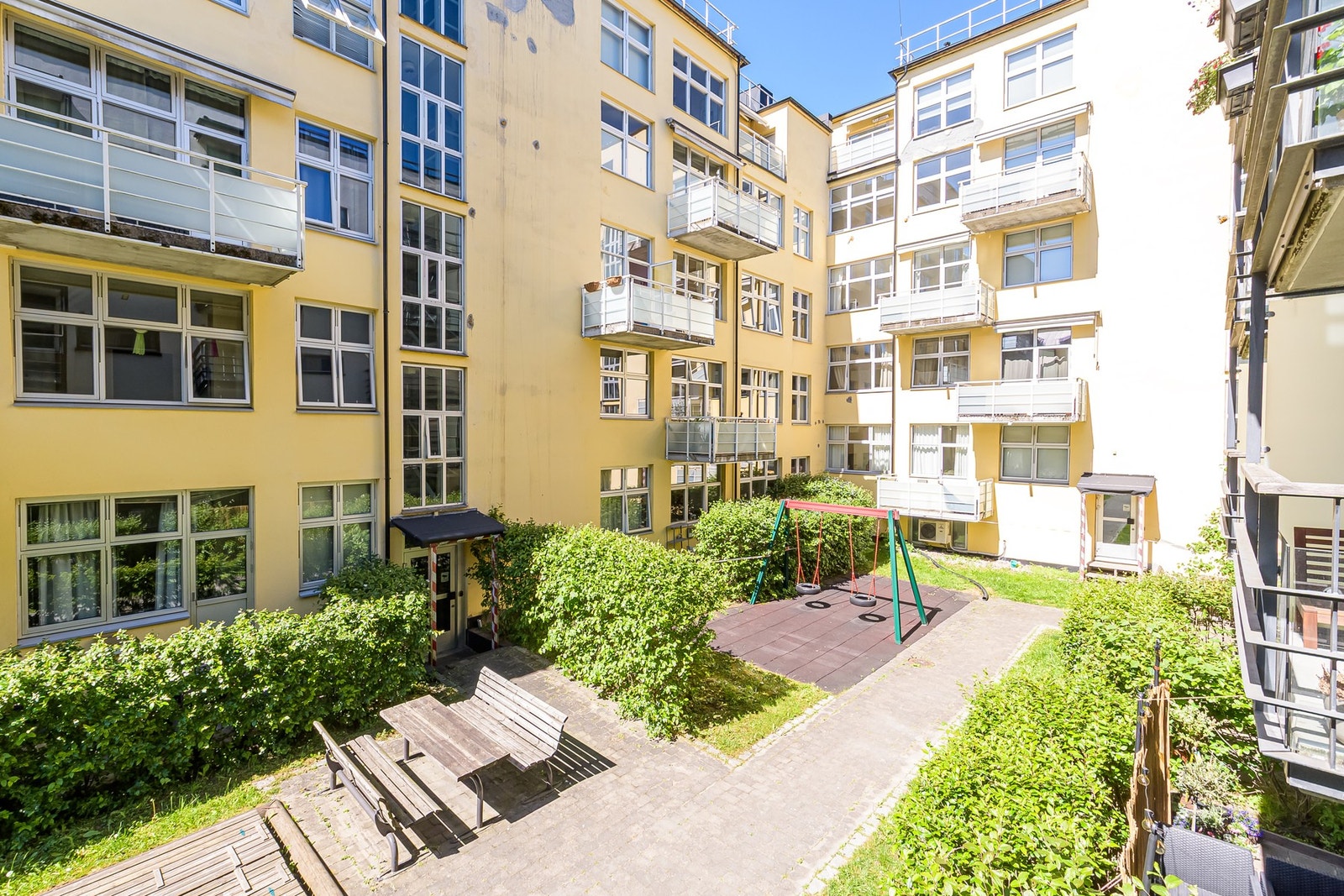 Tomten er pent opparbeidet med sittebenker, prydbusker og asfalterte internveier Galleribilde