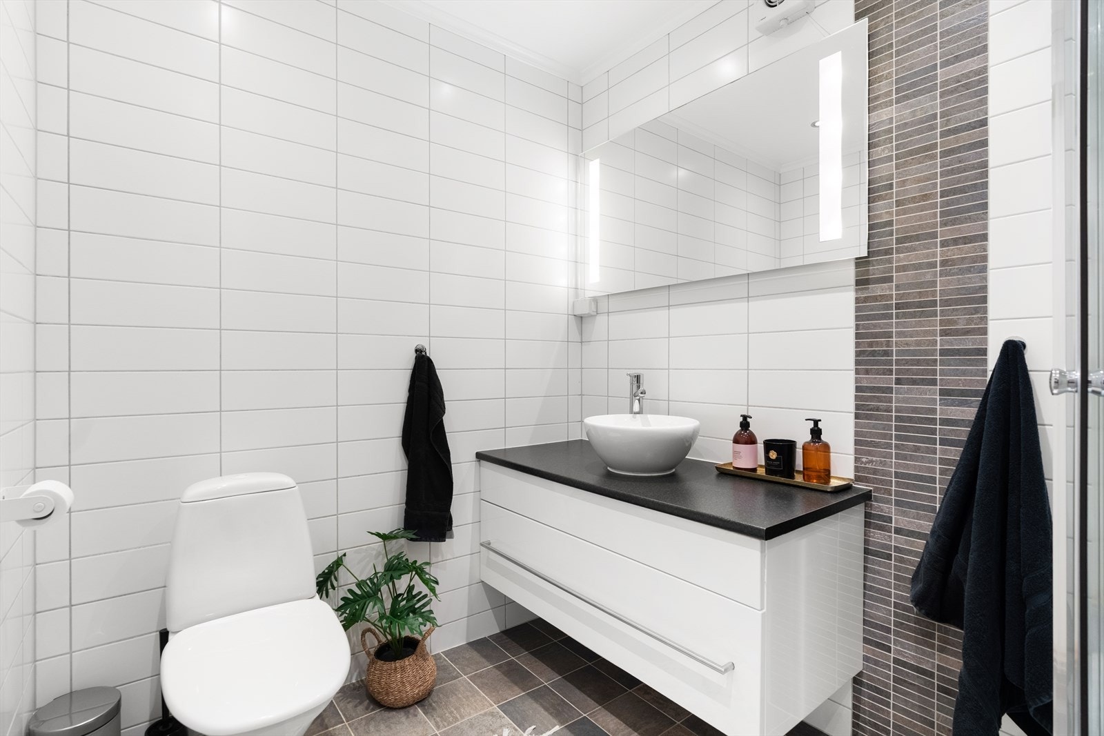 Rommet har lyse veggfliser, mørke gulvfliser, downlights og gulvvarme. Galleribilde