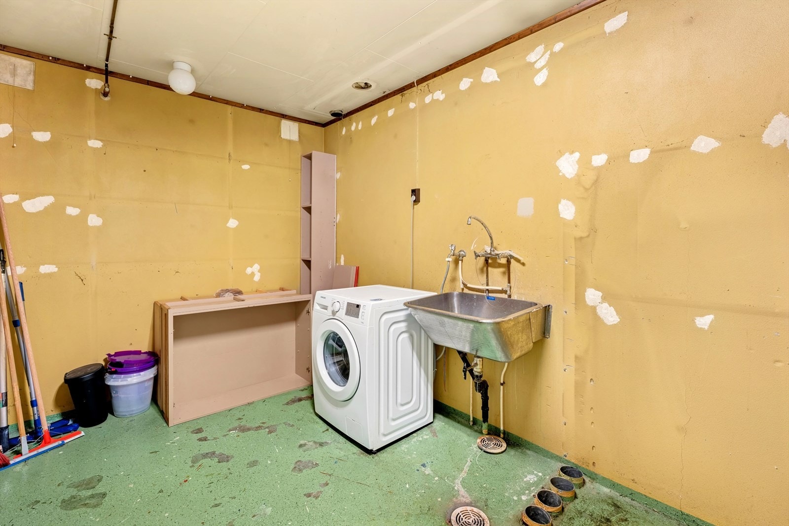 Vaskerom i underetasje er fra byggeår. Rommet har malt betongulv og vegger med malt puss. Et tidligere varme/ventilasjonsanlegg er demontert, noe som etterlater hull i gulv og vegger. Galleribilde