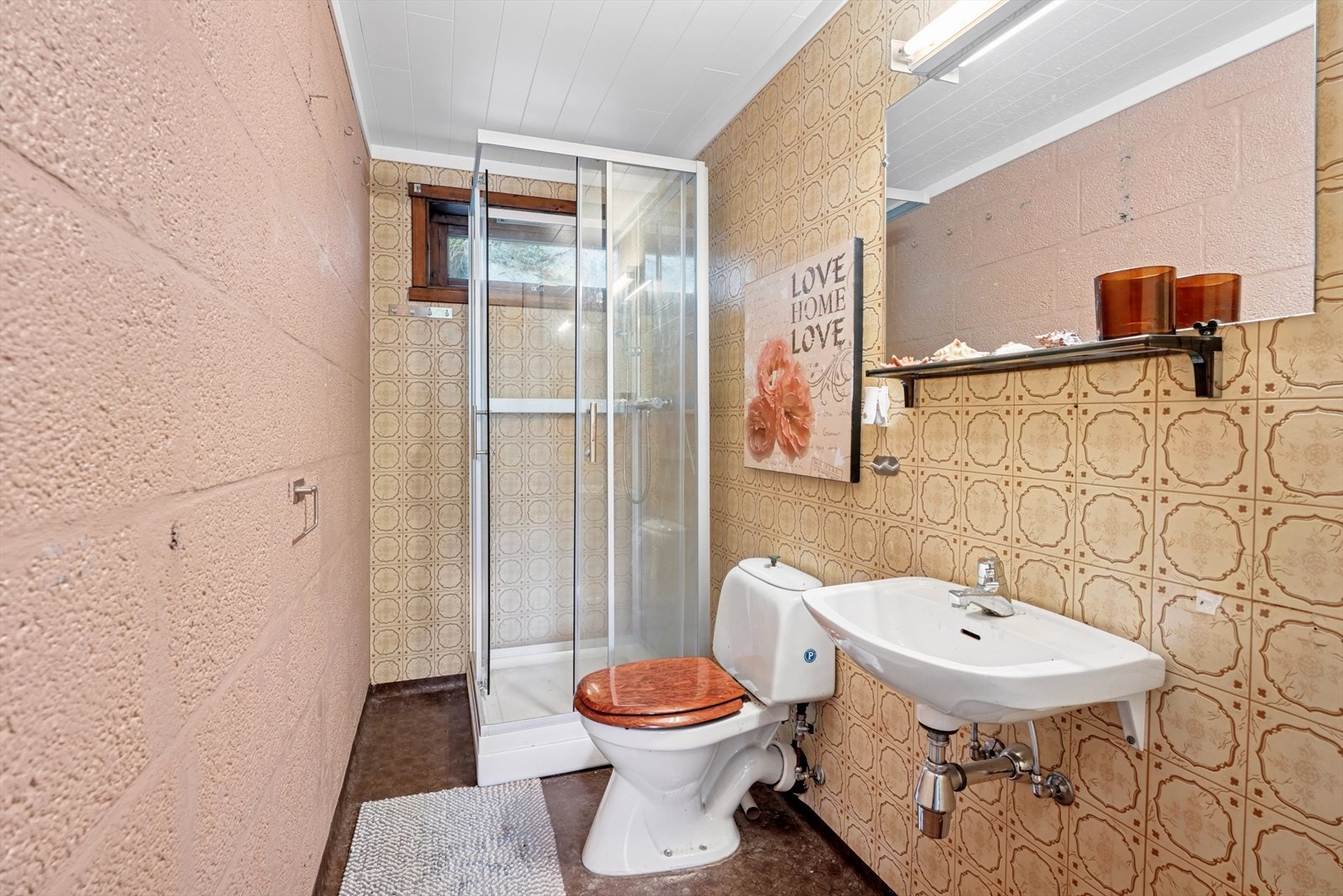 Badet i underetasje er fra byggeår. Rommet har belegg på gulv og baderomstapet på to vegger. Det er utstyrt med servant, klosett og dusjkabinett. Galleribilde