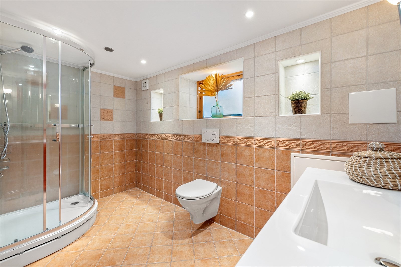 Pent flislagt bad med dusjkabinett og vegghengt toalett. Galleribilde