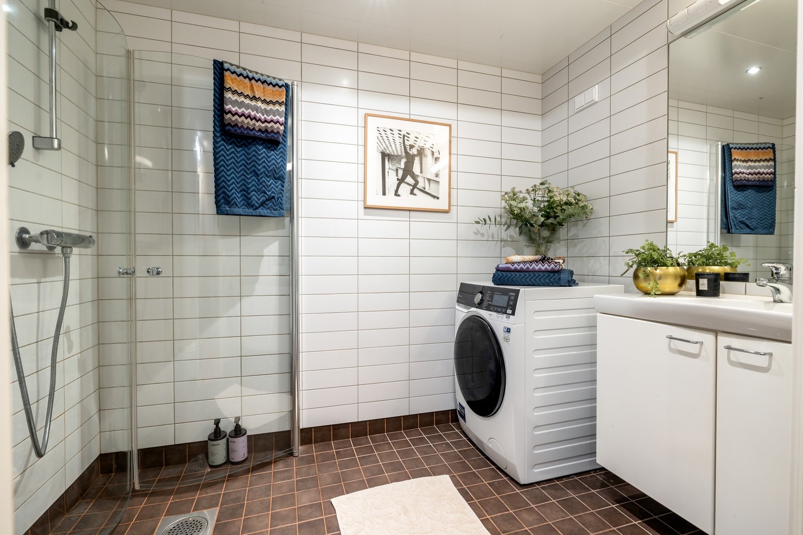 Badet er utstyrt med dusjhjørne med glassdører, vegghengt toalett, baderomsinnredning med heldekkende servant og opplegg for vaskemaskin. Galleribilde