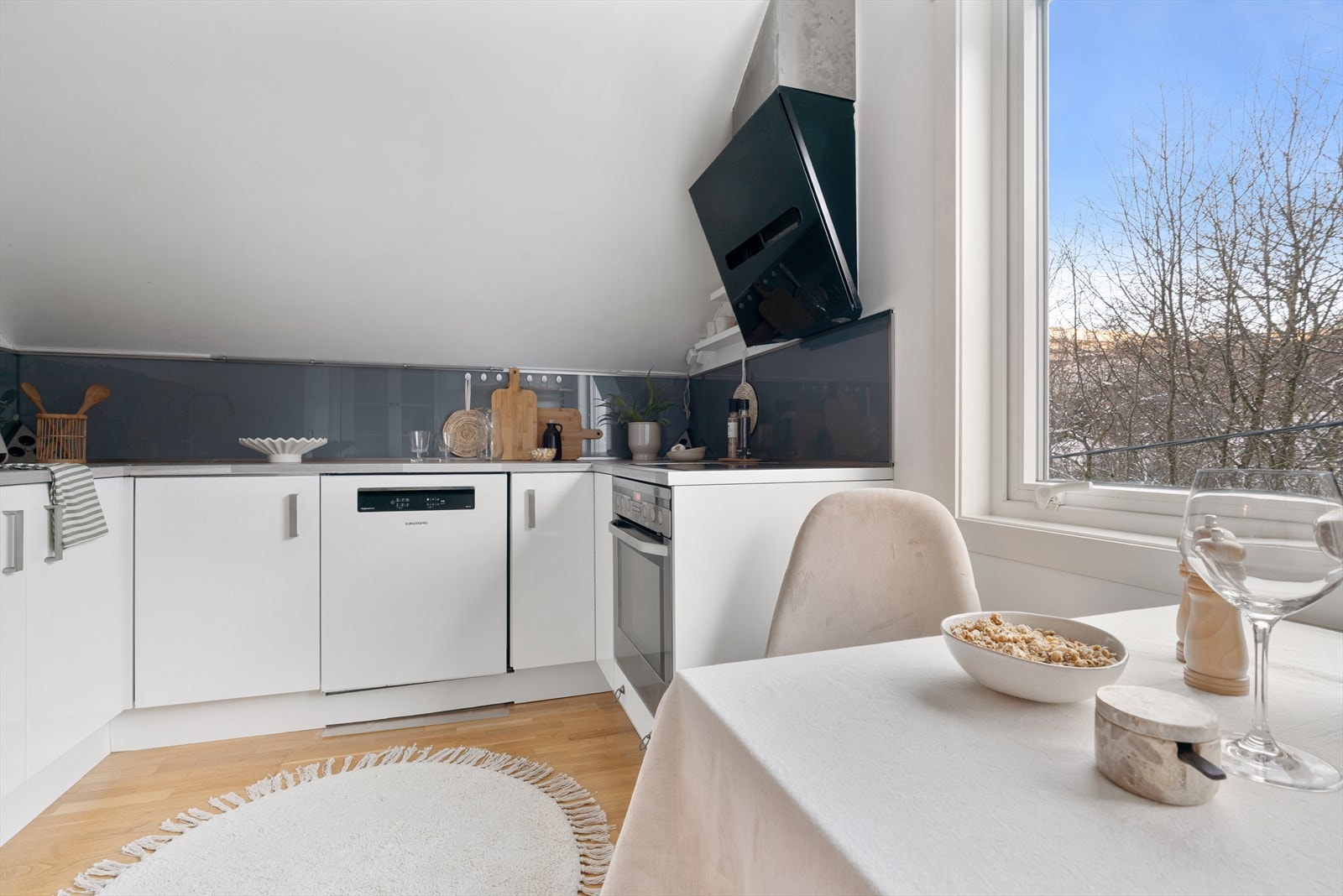 Kjøkkenet er innredet med hvite høyglans fronter og en laminat benkeplate med nedfelt stålvask. Galleribilde