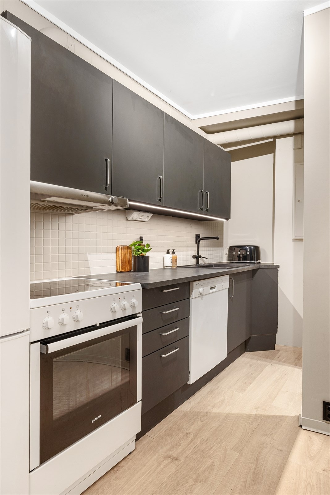 Kjøkken med benkeplate av laminat, vaskemaskin, komfyr og ny vask fra 2024. Galleribilde