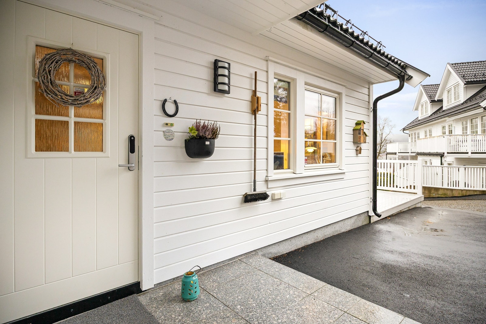 Asfaltert adkomstvei til boligens overbygde inngangsparti i 1. etasje. Mulig å etablerer lader for el-bil ved husveggen. Galleribilde