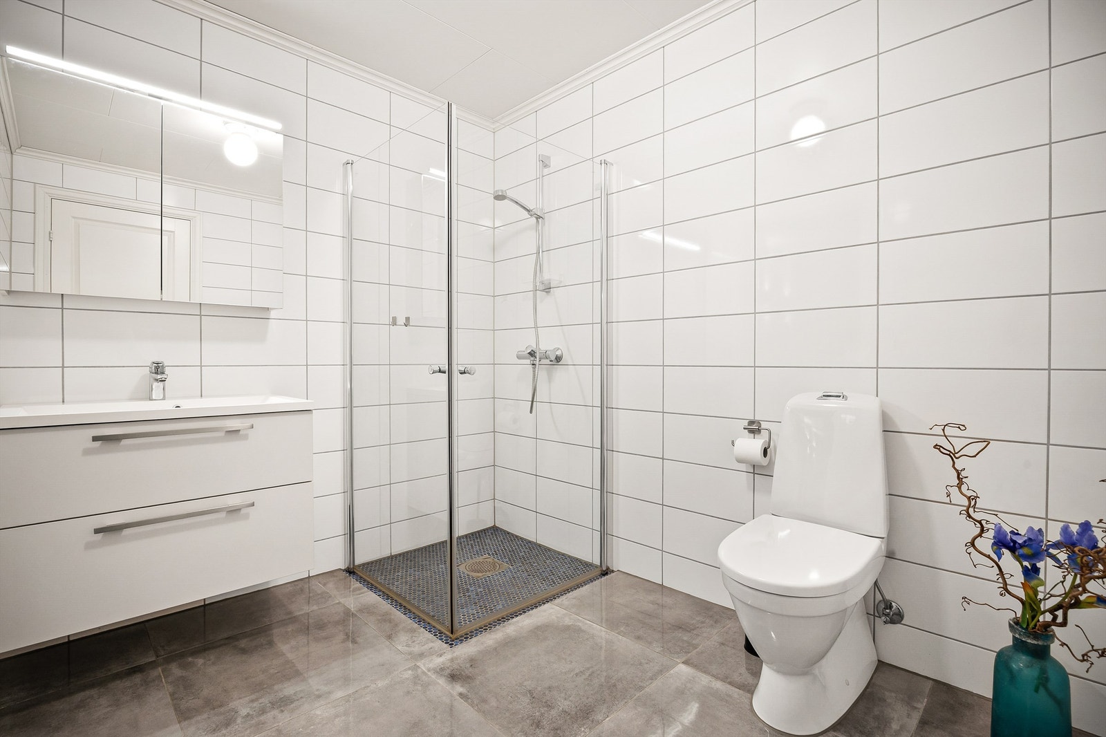 Lyst og pent bad med dusjhjørne som har foldedører av glass Galleribilde