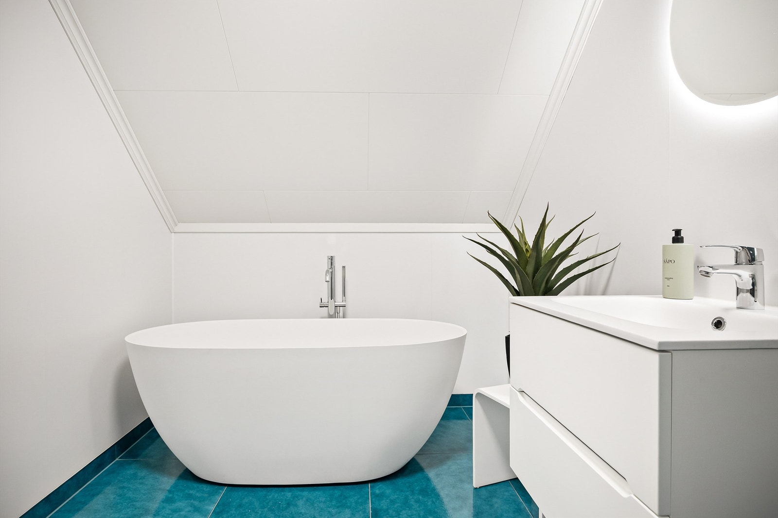 Badet har frittstående badekar og dusjhjørne med foldedører av glass Galleribilde