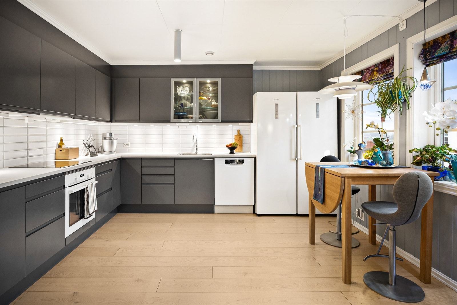 Moderne kjøkkeninnredning med over- og underskap samt vitrineskap i glatt utførelse Galleribilde