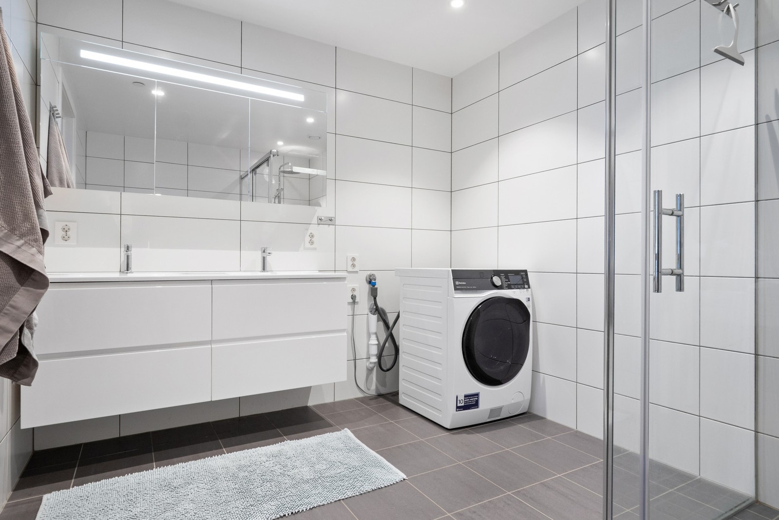 Baderomsinnredningen består av en servant med hvite skuffer og et speilskap med integrert belysning. Galleribilde