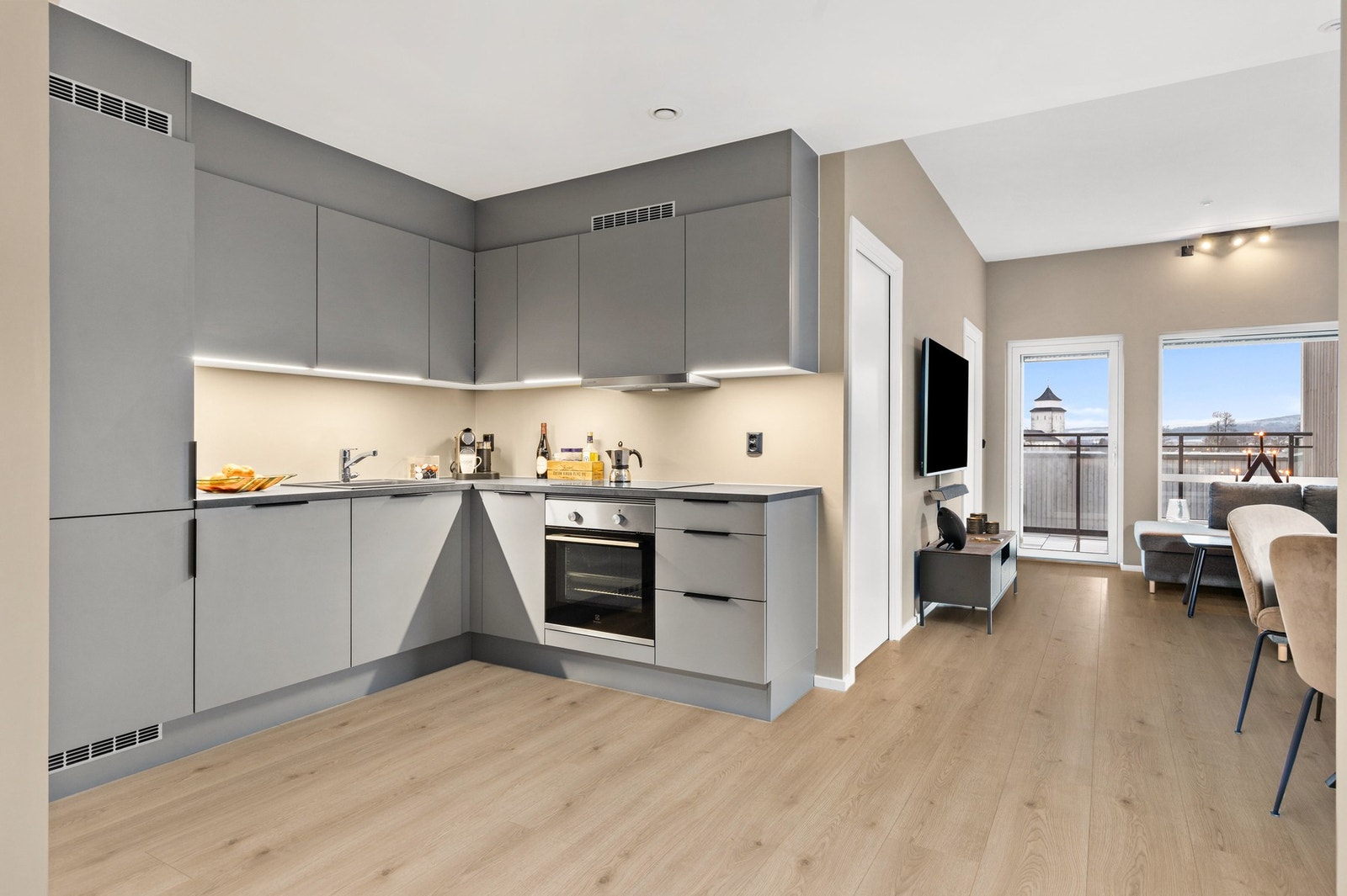 Leiligheten har et påkostet kjøkken som går helt til tak, med slette fronter, sorte håndtak og integrert LED-belysning under overskap Galleribilde