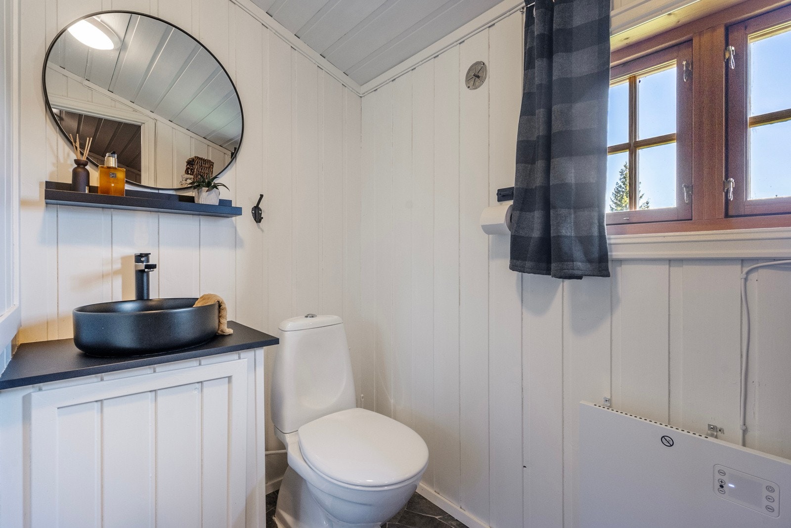 Badet er fra tilbyggingsår og har overflater av belegg på gulv og trepanel på vegger Galleribilde