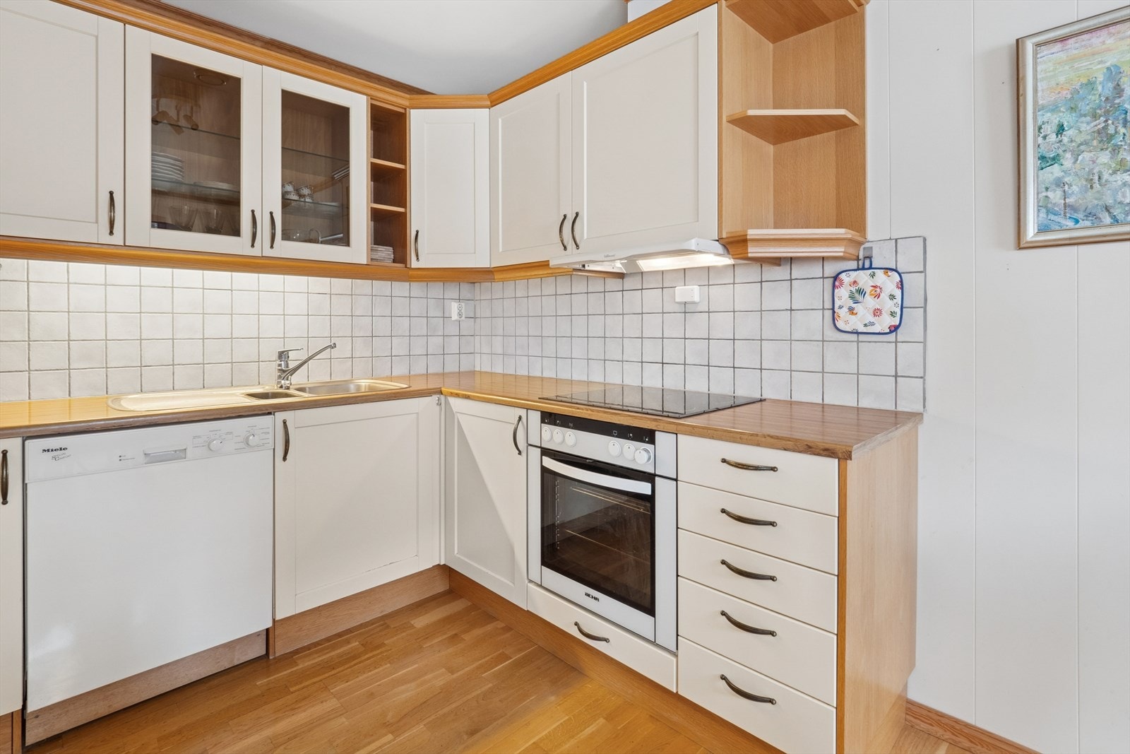 Fliser på veggen mellom underskap og overskap gir et elegant og lettstelt preg. Kjøkkenventilatoren med avtrekk ut sikrer god luftkvalitet. Galleribilde