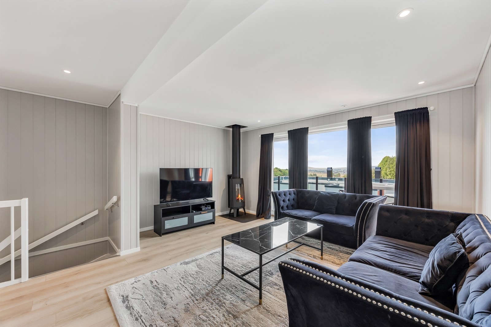 I stuen er det peisovn for vedfyring, samt store vindusflater som gir gode lysforhold. Galleribilde