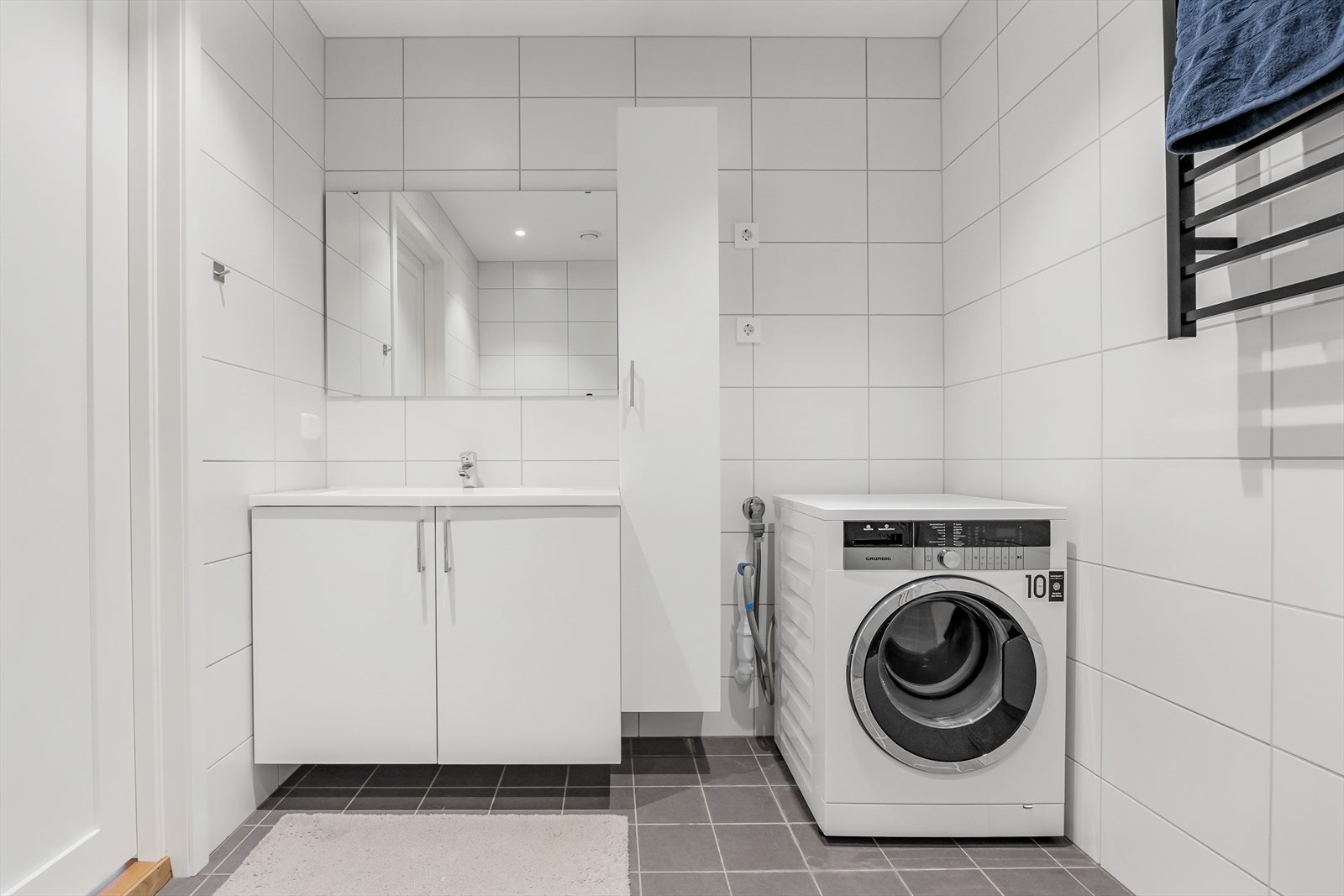 Vegghengt skap for ekstra oppbevaring på badet. Videre er det opplegg og plass for vaskemaskin. Galleribilde