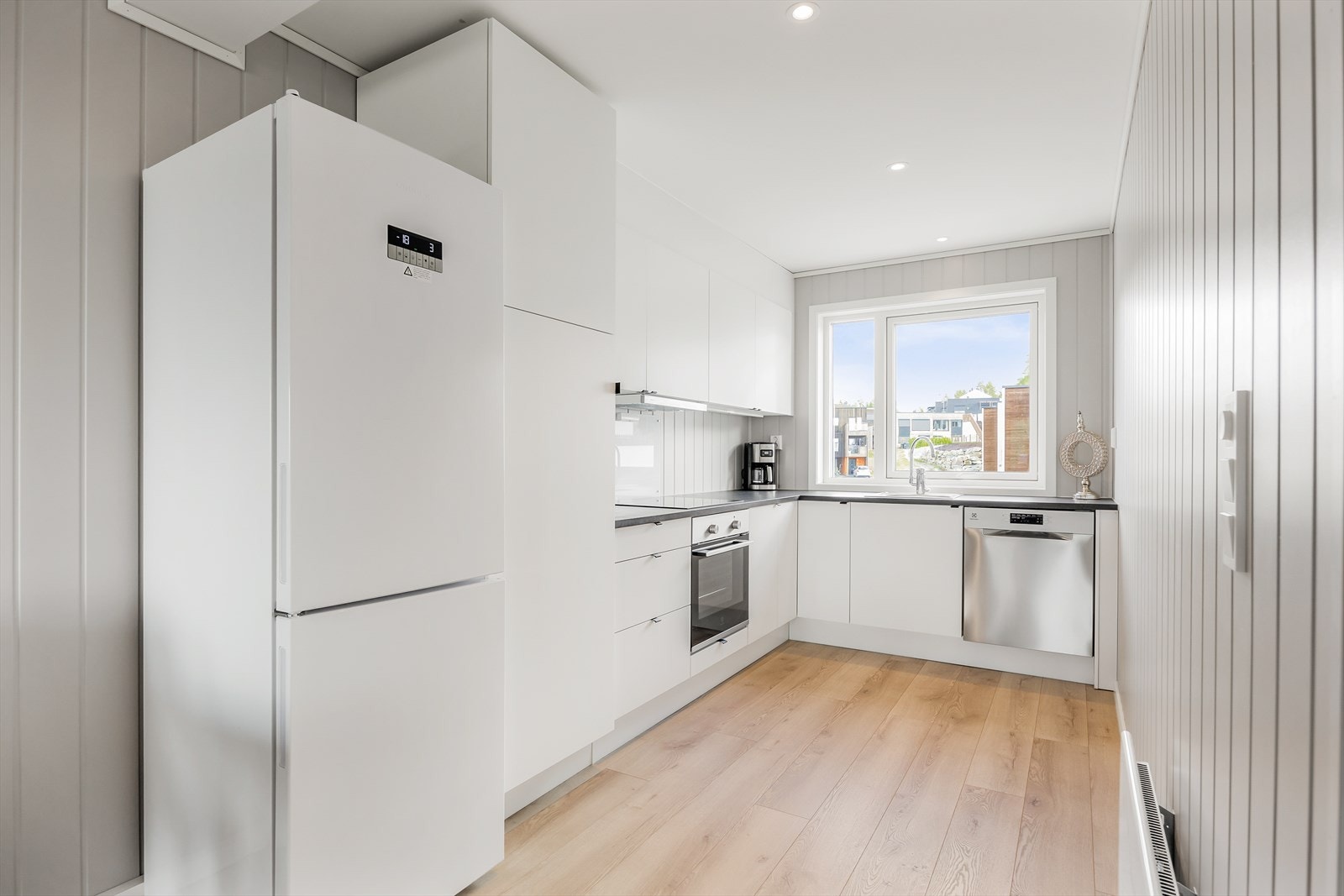 Fint og praktisk kjøkken med god skap- og benkeplass. Kjøkkeninnredningen har hvite, glatte fronter og laminert benkeplate. Det er monter backsplash bak kokesonen. Galleribilde