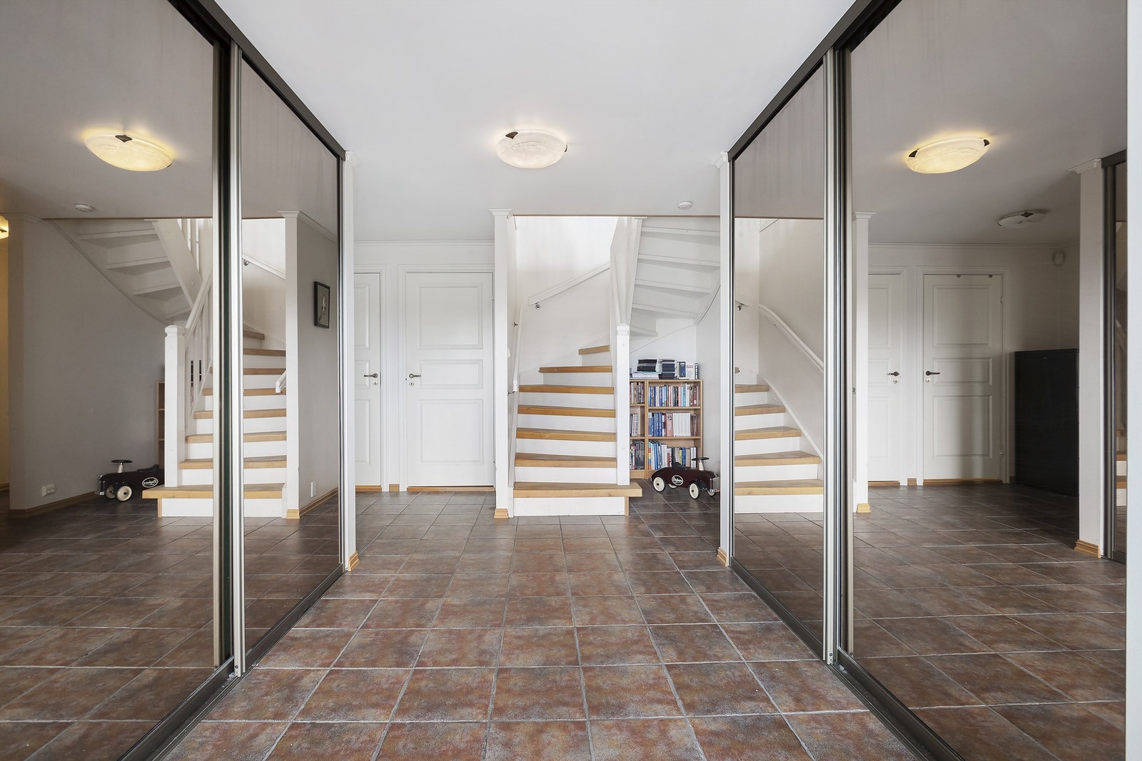 Man kommer inn i en romslig, flislagt entré med dobbel skyvedørsgarderobe Galleribilde