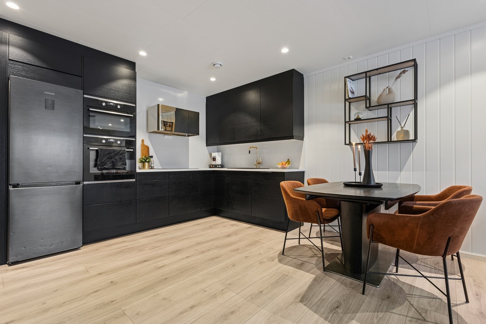 Stilrent kjøkken bestående av innredning med glatte fronter og en solid benkeplate i stein. Galleribilde