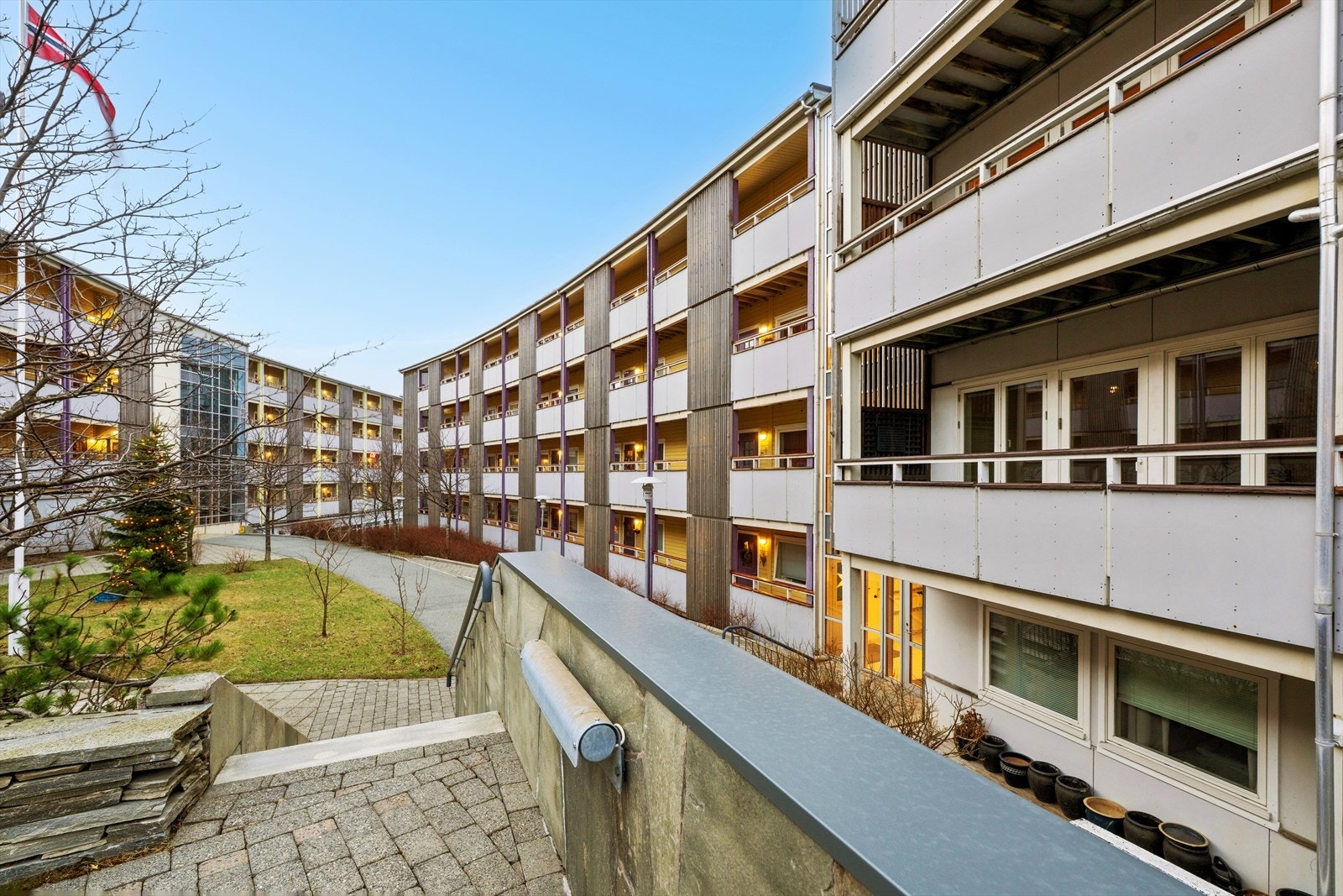 Flotte interne arealer med sitteplasser, prydbusker og brobelagte stier. Galleribilde