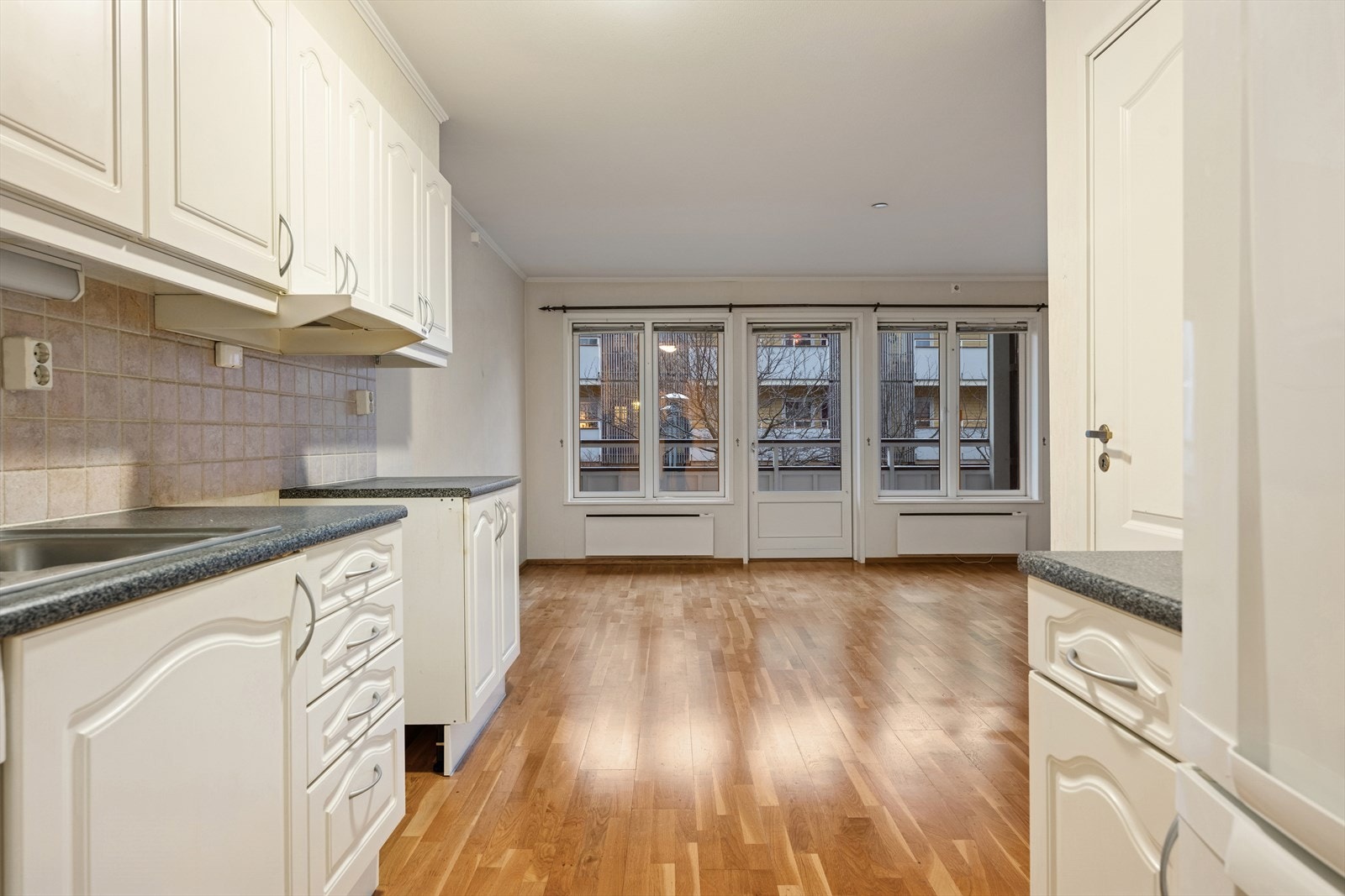 Kjøkkenet er innredet med profilerte fronter, fliser på vegg mellom over-og underskap, dobbel stålvask med benkebeslag og opplegg for oppvaskmaskin. Galleribilde