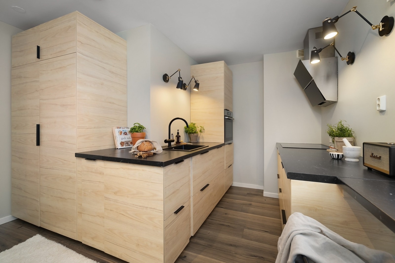 Innredningen har lyse, glatte fronter, benkeplate av laminat og oppvaskkum av kompositt med ett-greps armatur - begge av sort utførelse Galleribilde