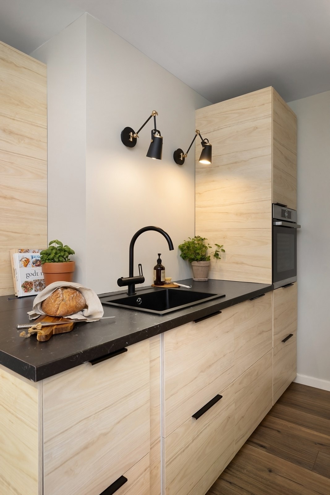 Integrerte hvitevarer som stekeovn, nedfelt koketopp med kullfilterventilator over, kjøleskap, fryseskap og oppvaskmaskin Galleribilde