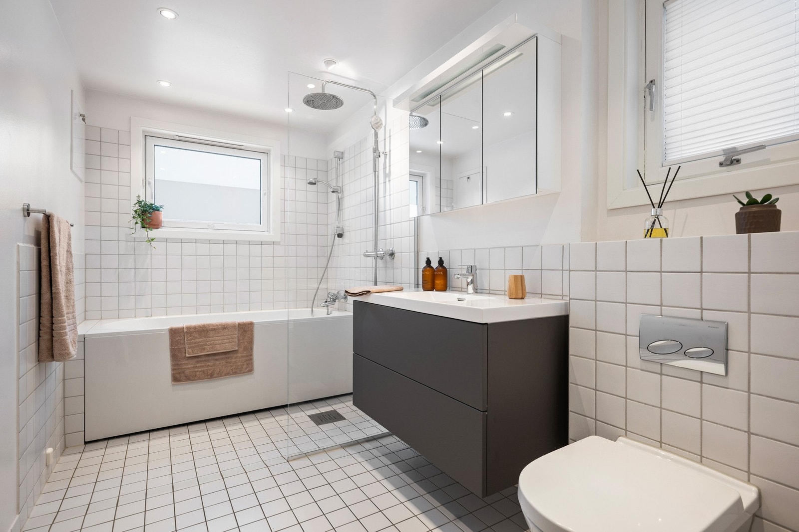 Romslig baderom i 2. etasje, oppusset i 2014, med flislagt gulv med gulvvarme, badekar, dusjhjørne med glassvegg og vegghengt toalett. Galleribilde