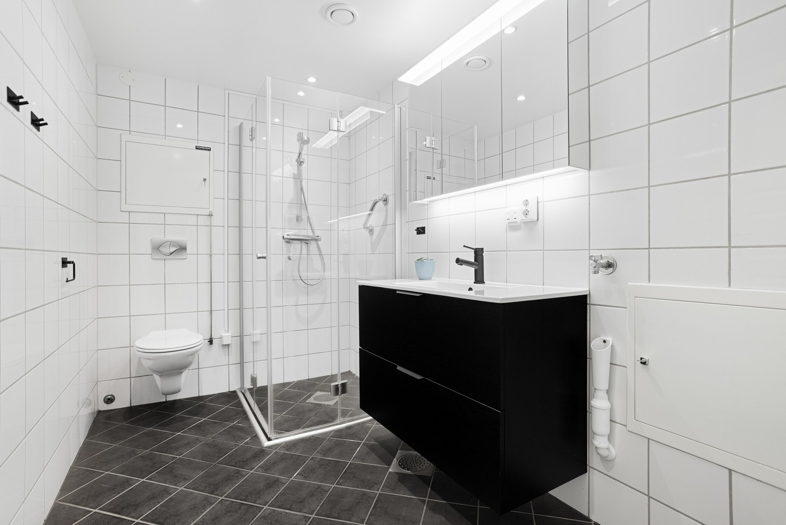 Bad/vaskerom med flis på vegger og gulv, opplegg til vaskemaskin og baderomsinnredning fra 2024 Galleribilde