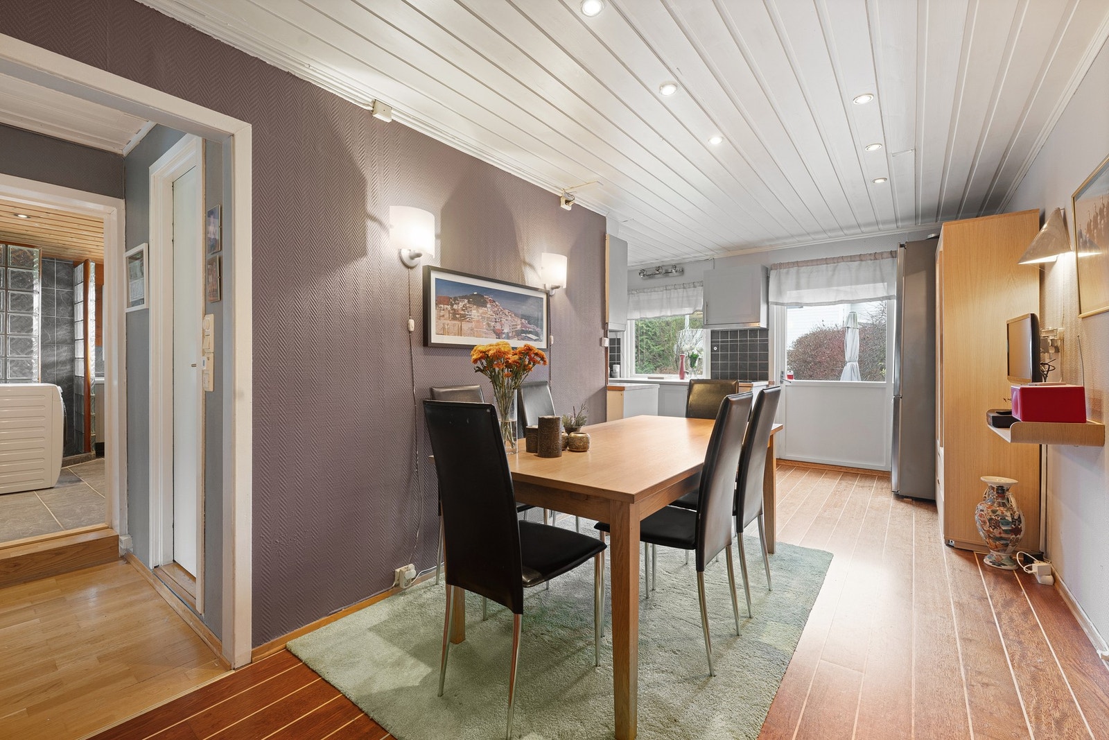 Boligen har et lyst og trivelig kjøkken med delvis åpen løsning mot spisestuen - en sosial og praktisk planløsning som gjør det enkelt å holde kontakt med gjester. Galleribilde