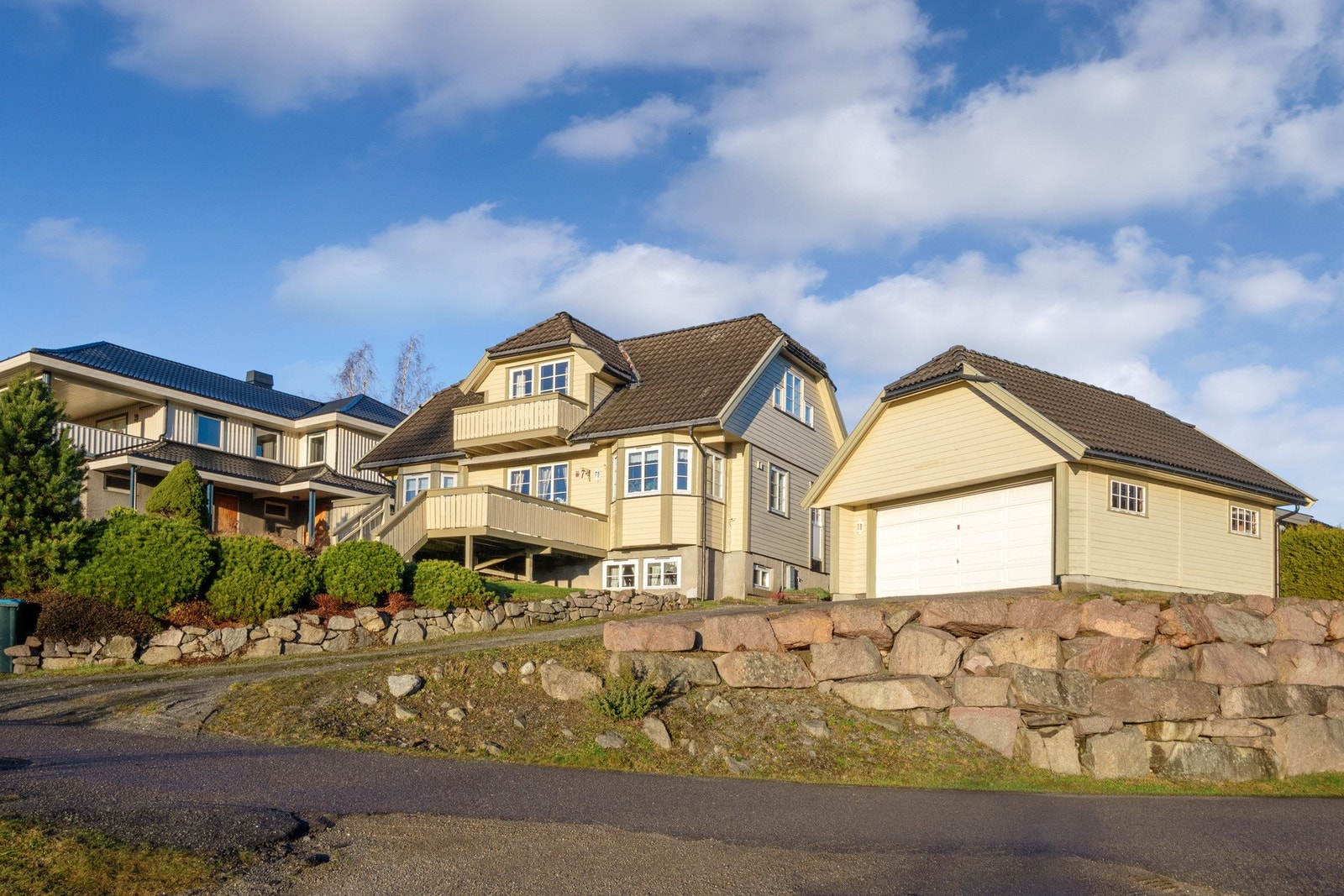 Selve huset ligger fritt til på en romslig hjørnetomt, opparbeidet med hekker, gressplen, prydbusker og støttemurer av naturstein. Galleribilde