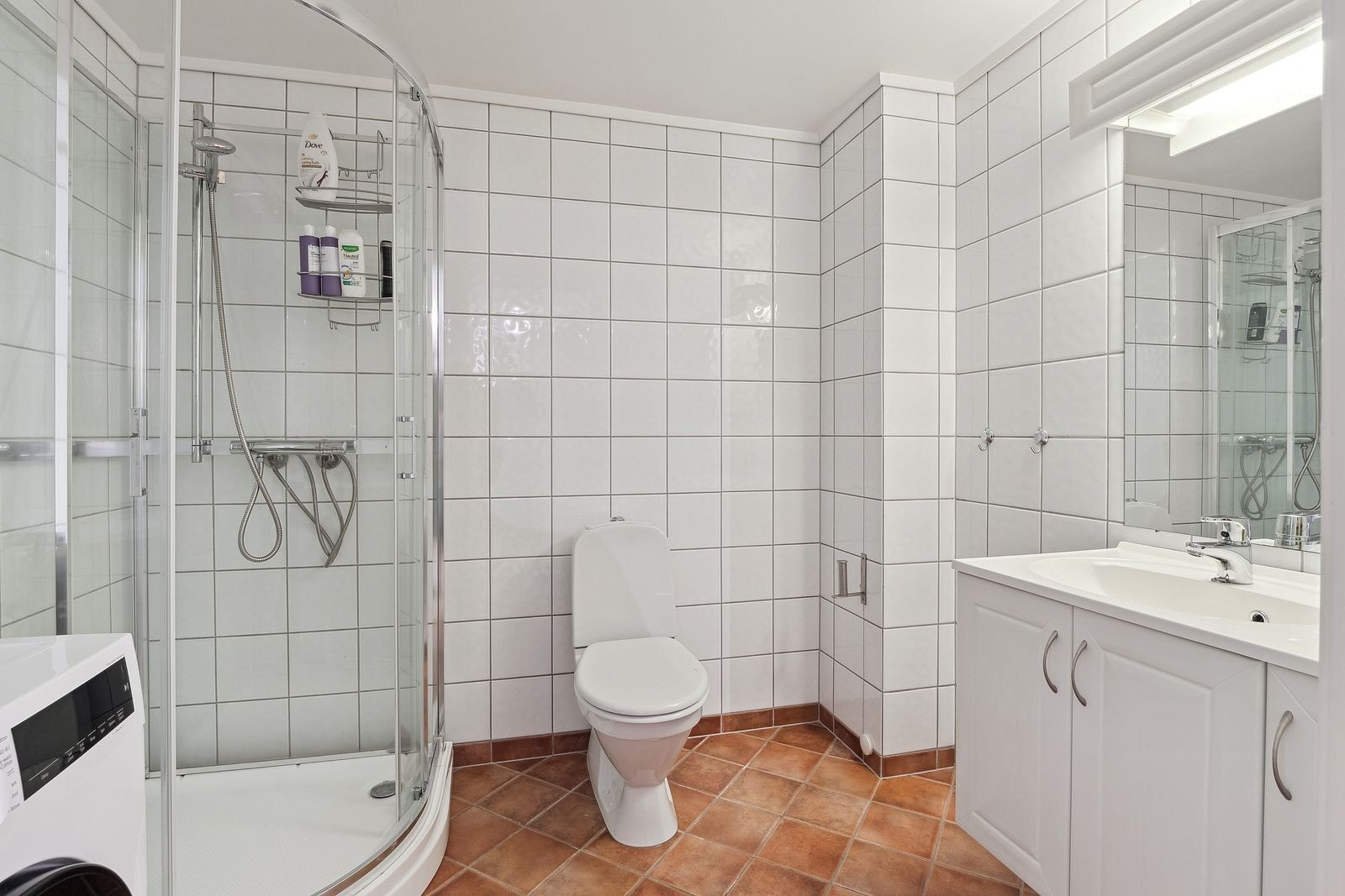Pent flislagt bad med dusjkabinett, toalett og servant m/innredning. Vaskemaskin følger med. Galleribilde