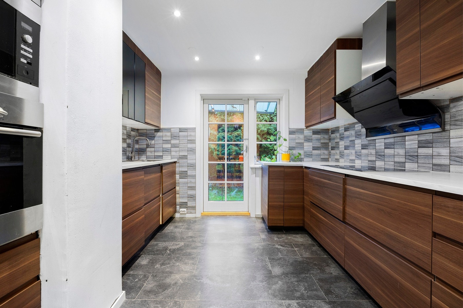 Separat kjøkkenløsning med direkte utgang til hage. Kjøkkenet har glatte fronter og benkeplate av laminat Galleribilde